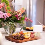 flowers and a meat and cheese board with grapes