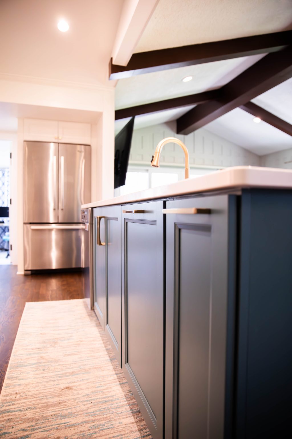 Blue island with cabinetry below custom wood beams installed by Ottawa Hills kitchen remodeler