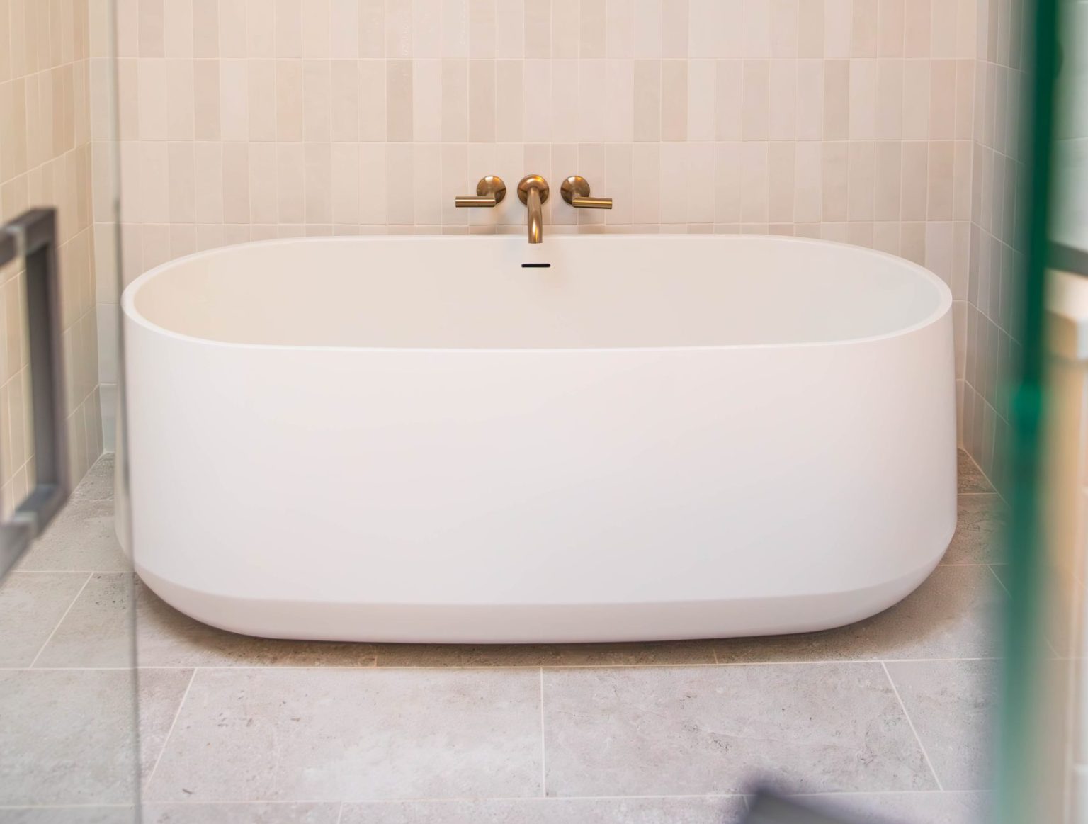 Freestanding oval soaking bathtub with gold faucets installed by bathroom remodeler in Sylvania