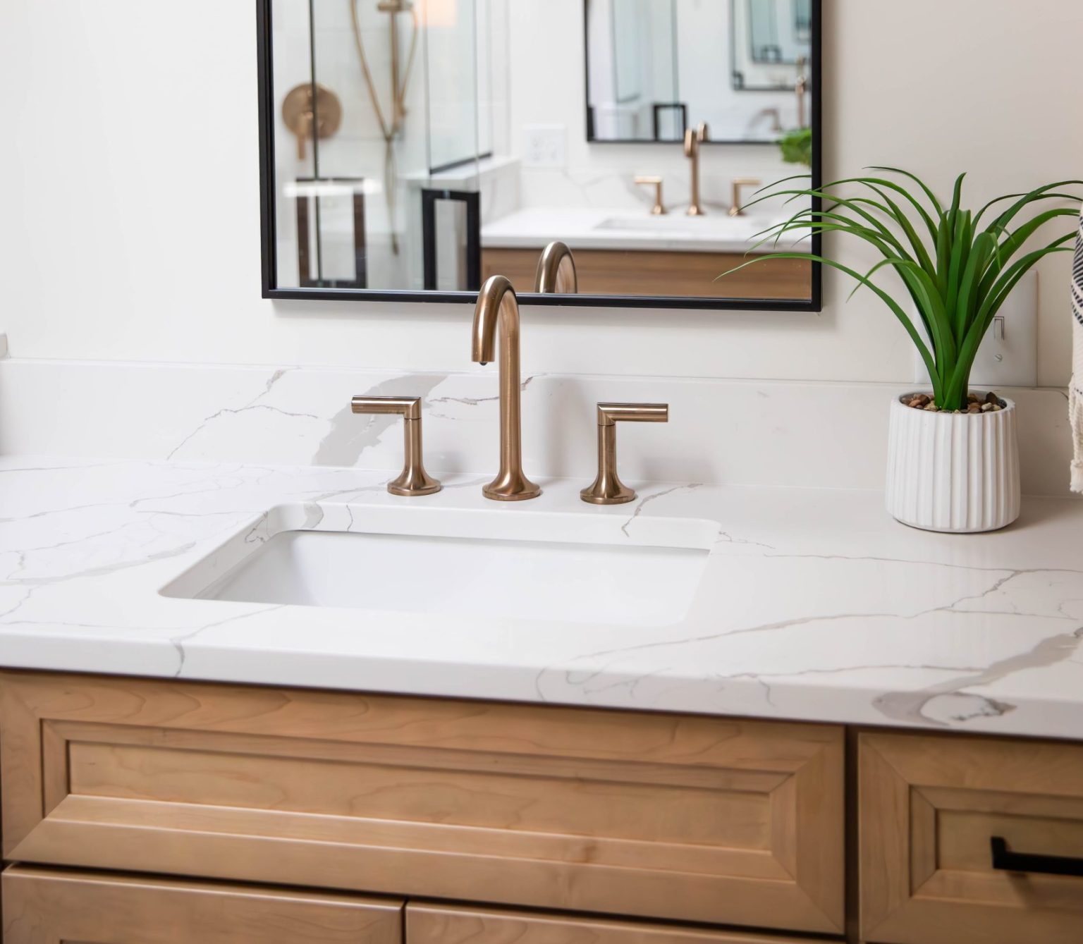 Brass faucet and rectangular white sink installed by Sylvania bathroom remodeler